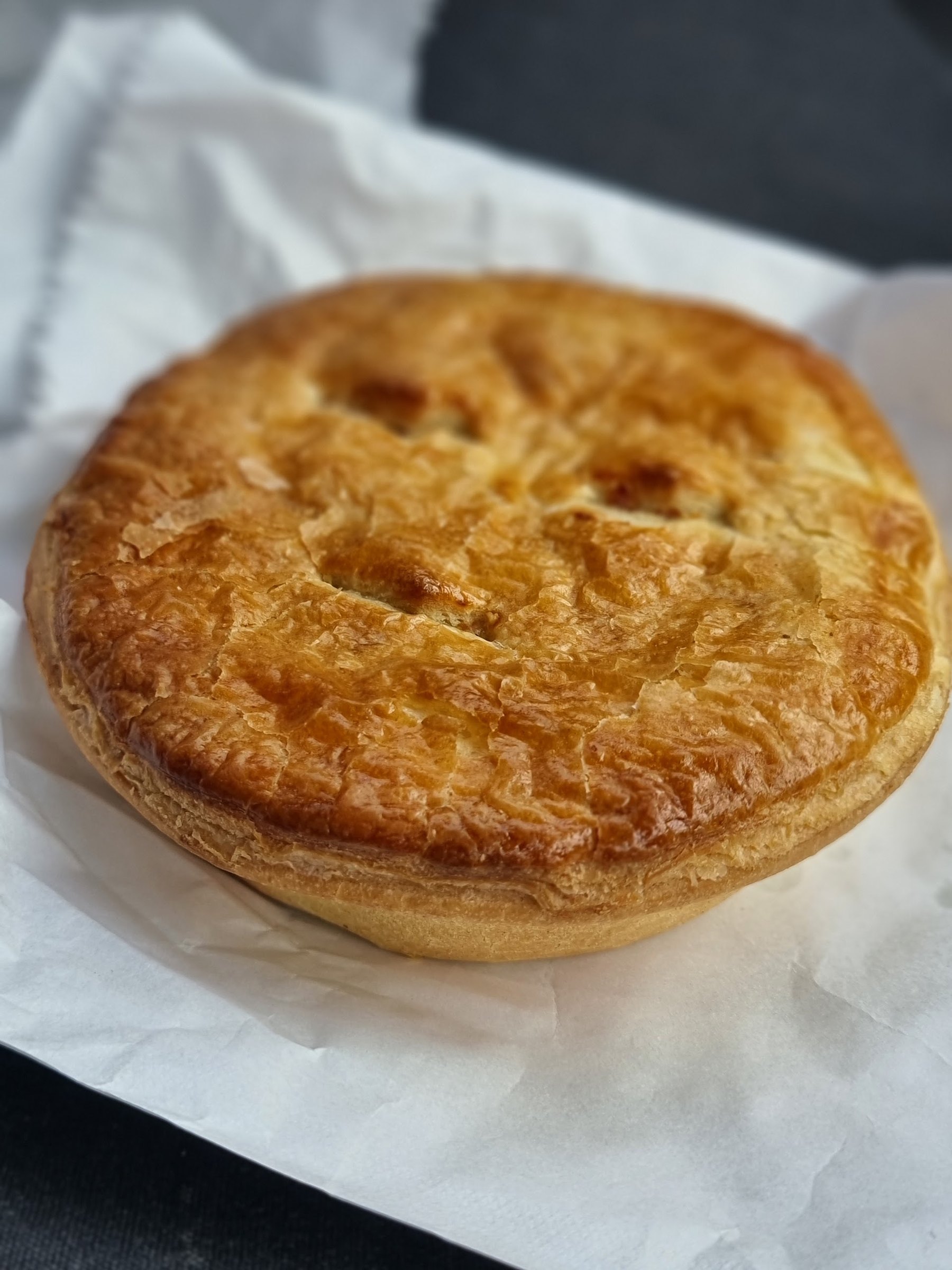 A golden Pie Haus steak pie on white paper