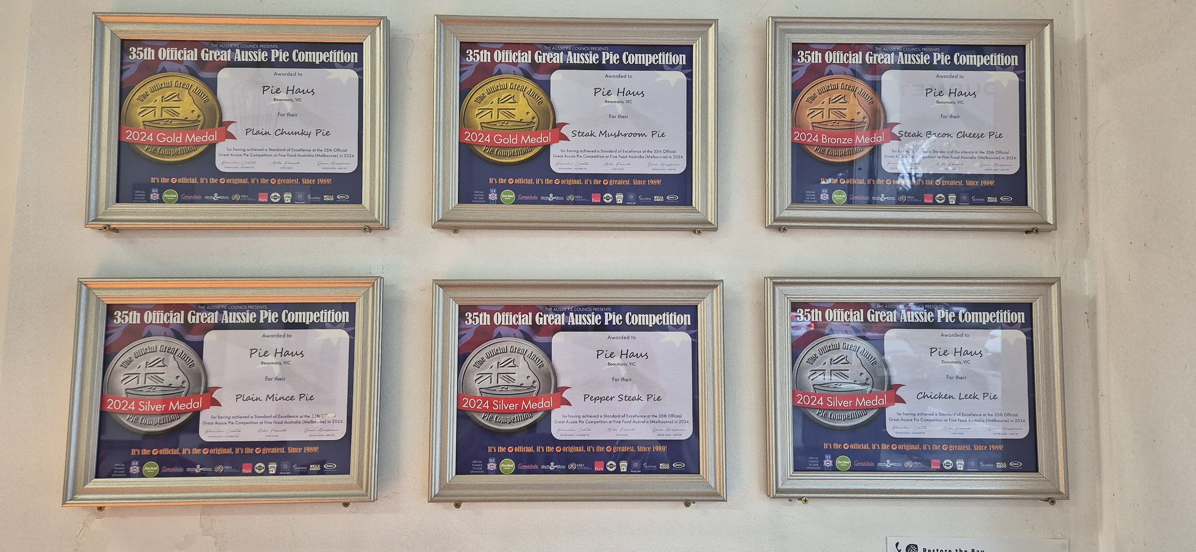 Our six 2024 Great Aussie Pie Competition certificates on the shop wall